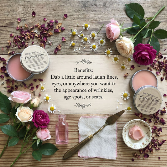 Rosebud Balm with flowers and text on a wooden surface